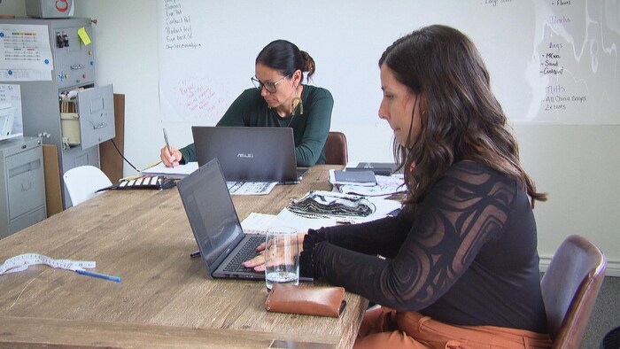 Trisha Pitura et Mélanie Bernard assise à leur bureau devant des ordinateurs portables.
