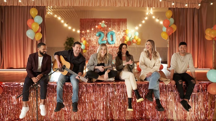 Les six interprètes de Mixmania sont assis sur une scène avec les ballons en arrière-plan. Ils semblent avoir un fou rire.