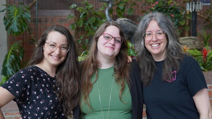 Trois femmes souriantes qui posent.