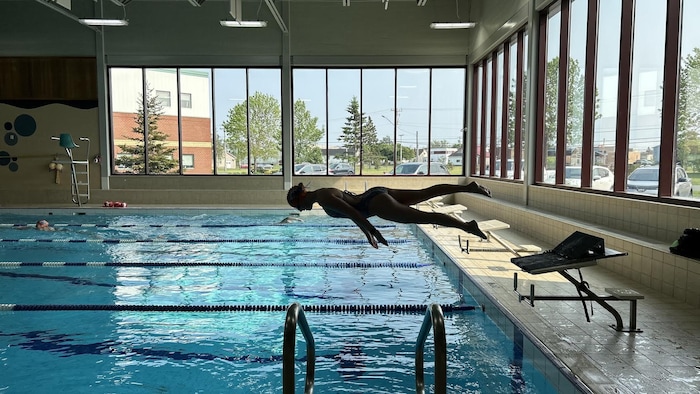 Une jeune femme qui plonge dans la piscine. Elle est à l'horizontal.