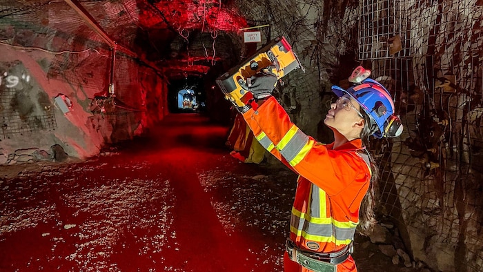 Une étudiante tient à bout de bras une machine pour faire des mesures.