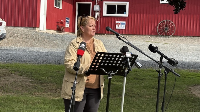 Danielle Connell parle dans un micro, à l'extérieur de la ferme Schuttens Holsteins