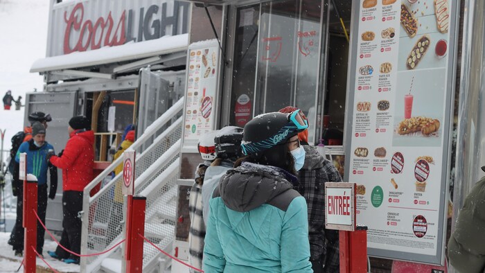 Une file de skieurs devant un kiosque de vente de nourriture.