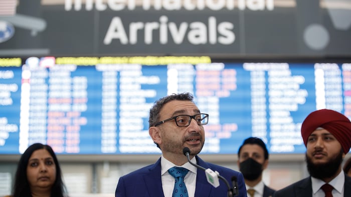 Transport Minister Omar Alghabra speaks in front of billboard at Pearson Airport. 