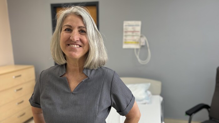 Isabelle Moisan pose dans une chambre d'un CHSLD. Elle regarde la caméra avec un grand sourire. 