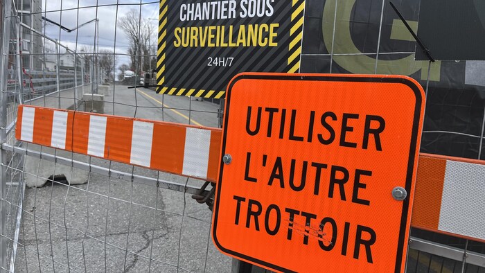 Une pancarte où on peut lire utiliser l'autre trottoir.