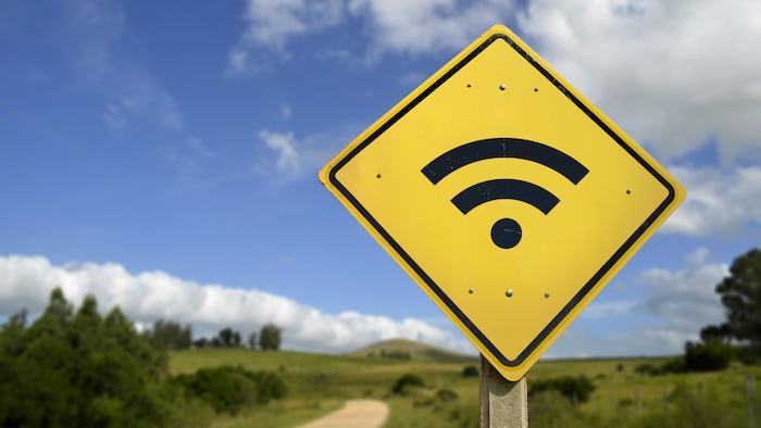 Un panneau de signalisation avec un symbole de signal wi-fi dans un environnement rural.