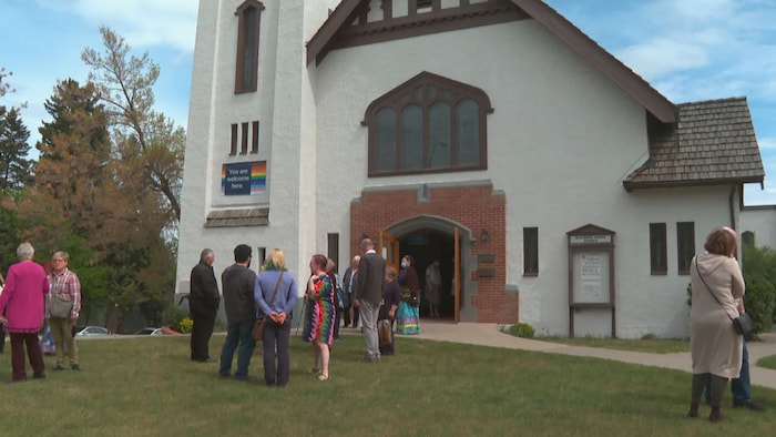 Des paroissiens sont réunis pour regarder la nouvelle bannière accrochée à l'extérieur de l'église, le 29 mai 2022.  