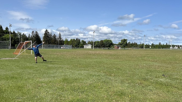 Un jeune athlète lance un javelot dans un terrain de soccer.