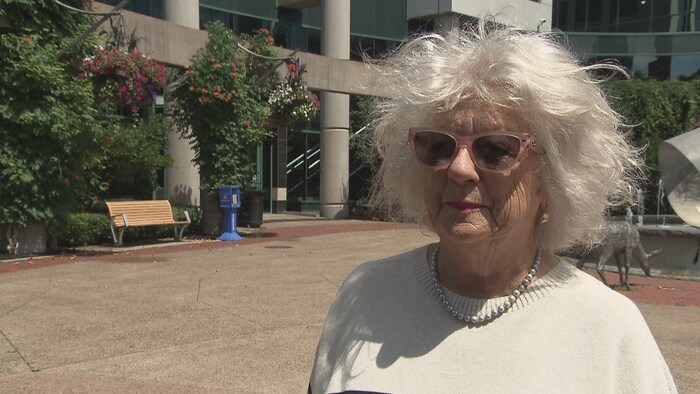 Une dame portant des lunettes à l'extérieur de l'Hôtel de ville.