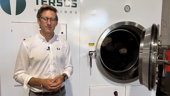Peter Whitcomb se tient devant une machine floquée de la marque Tersus Solutions. 