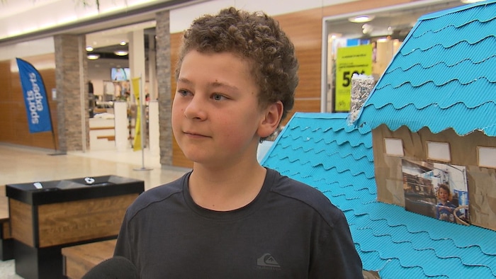 Un enfant en entrevue devant un kiosque dans un centre d'achat.