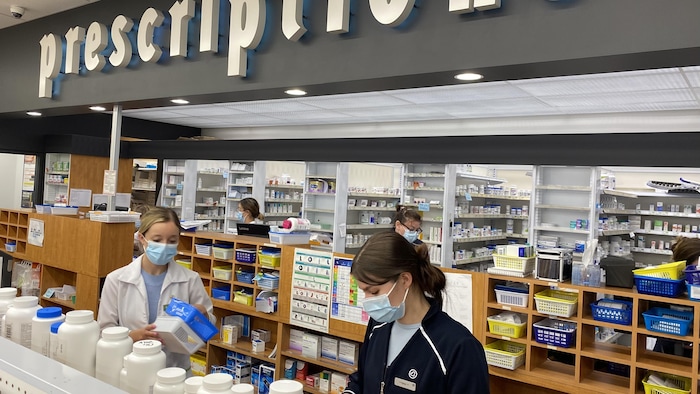 Deux employés d'une pharmacie préparent une prescription.