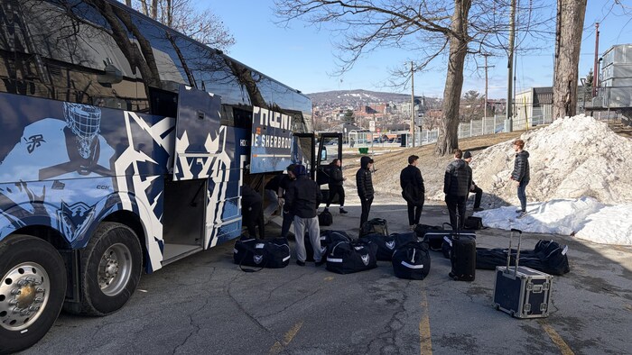 Un autobus avec des sacs et des jeunes hommes.