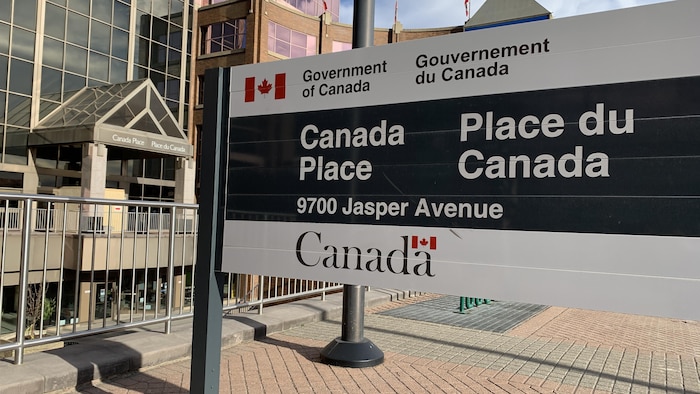 Affice noire et blanche avec le logo officiel du gouvernement du Canada et l'inscription Place du Canada. Journée partiellement ensoleillée d'automne.