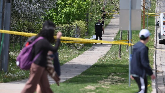 Des écoliers passent devant un cordon de police.