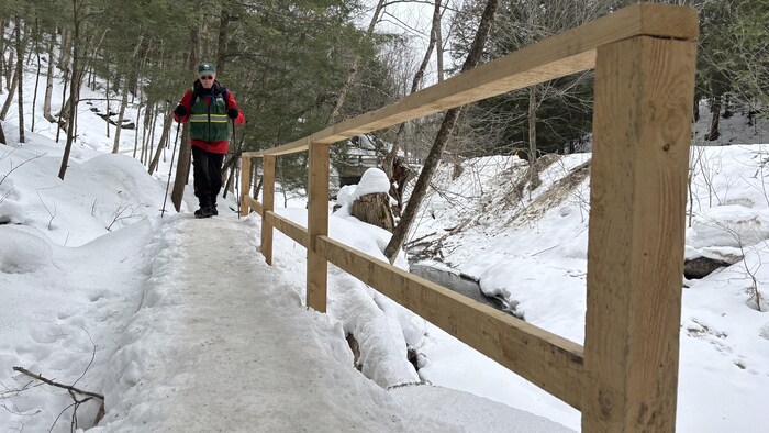 Un homme qui marche sur un pont en bois.