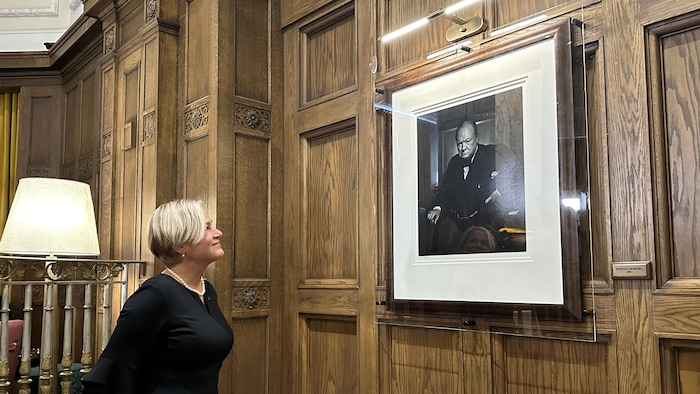 Une femme qui regarde le portrait de Winston Churchill exposé sur un mur au Château Laurier.