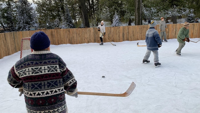 Des enfants qui jouent au hockey sur une patinoire extérieure.
