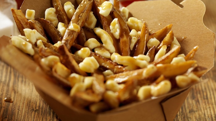 Gros plan d'une poutine dans une boîte en carton.