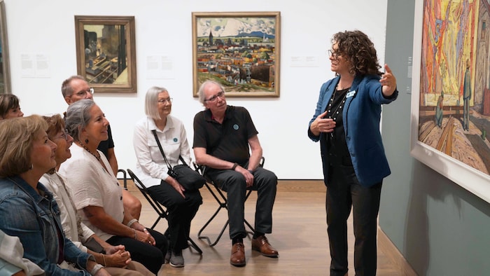 Une femme debout qui parle devant plusieurs personnes assises