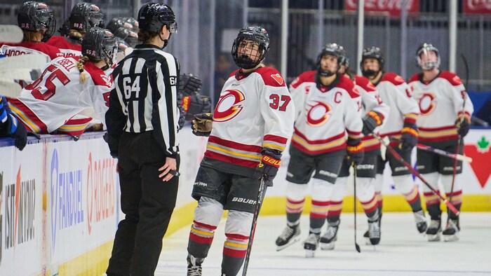 Une joueuse de hockey donne la main à des coéquipières au banc de son équipe.