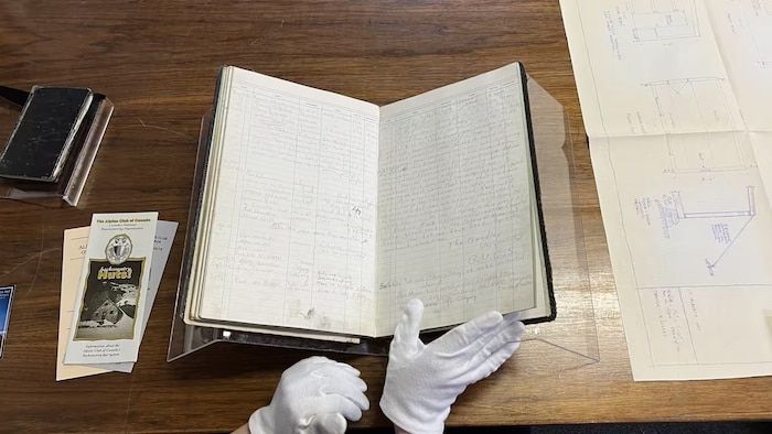 Une archiviste du musée Whyte Museum of the Canadian Rockies passe à travers les pages d’un registre d’alpinistes du refuge du col Abbot. 