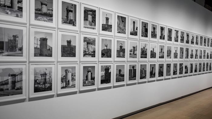 Plusieurs photographies accrochées sur un mur d'exposition dans une galerie.