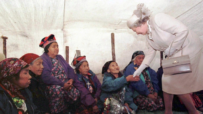 La reine Élisabeth II serre la main d'une aînée innue à l'intérieur d'une tente de chasse.