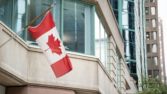 Un drapeau du Canada flotte contre un édifice.