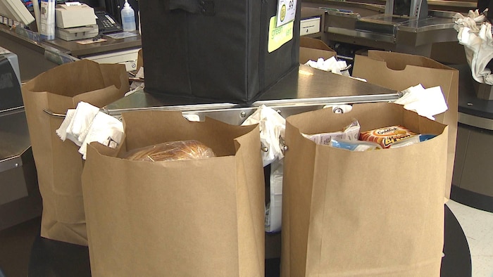 Des sacs en papier remplis d'aliments sur un tourniquet à l'épicerie.