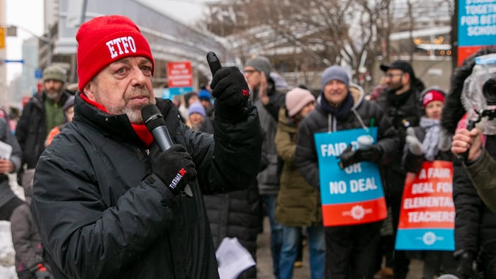 Sam Hammond, président de la Fédération des enseignantes et des enseignants de l’élémentaire de l’Ontario tient un micro devant quelques manifestants lors de la grève de son syndicat à Toronto.