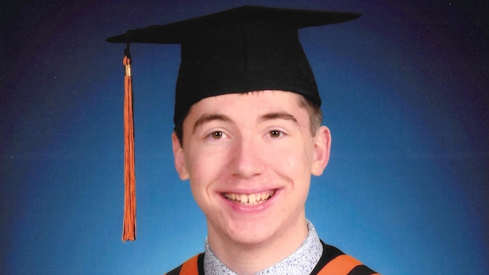 Un étudiant pose avec un diplôme dans sa main droite