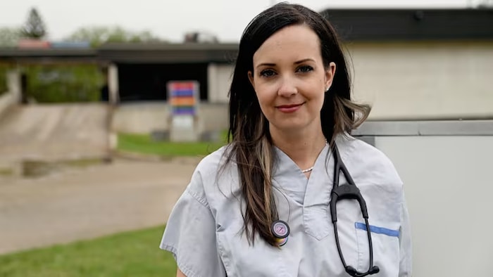 Une femme en uniforme de médecin se tien debout.