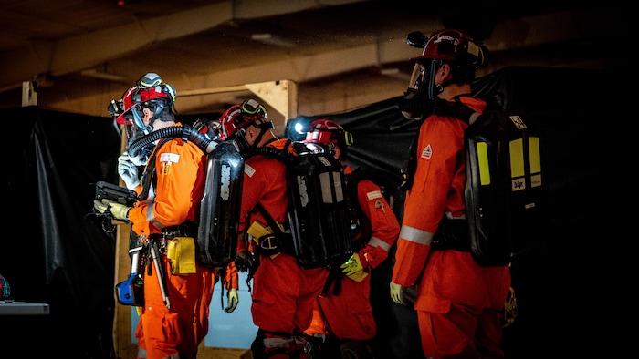 Un groupe de sauveteurs se déplace en groupe dans une pièce sombre.