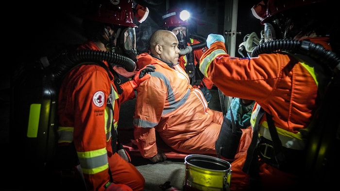 Des sauveteurs sont attroupés devant un homme qui simule une blessure.