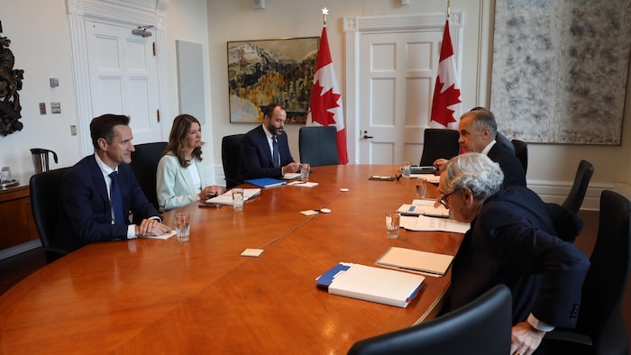 Danielle Smith et Mark Carney sont assis face-à-face à une table.