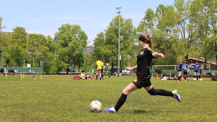 Une personne court après un ballon de soccer.