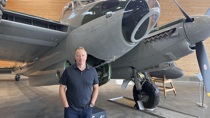 Un homme qui pose devant un avion.