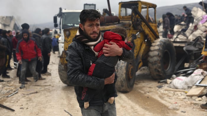 A man carries the body of an earthquake victim in the village of Besnia near the Turkish border, Syria, Monday, February 6, 2023.