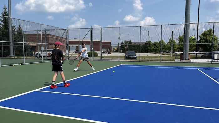 Deux joueurs jouent sur un côté du court de tennis.