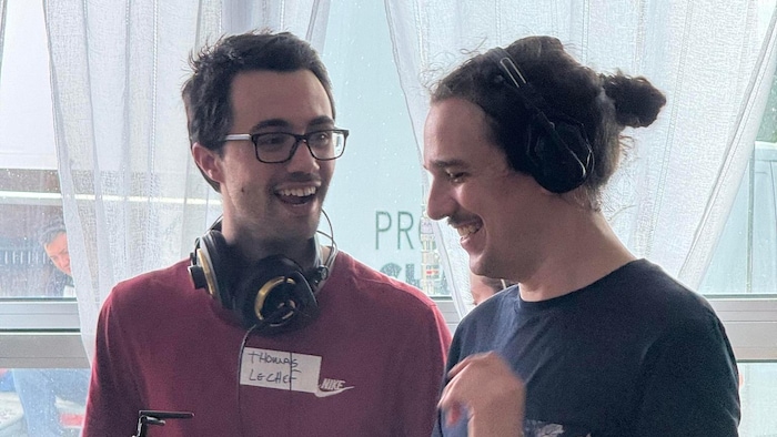 Deux hommes souriants en pleine discussion. Ils sont debout autour d'équipements de cinéma.