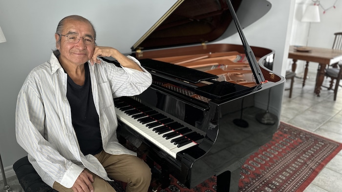 Tomson Highway assis aux côtés d'un piano.