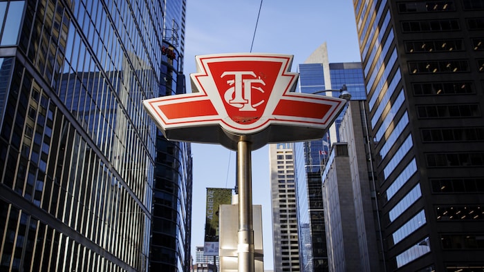 Affiche de la Commission de transport de Toronto sur un poteau avec des édifices en arrière-plan.