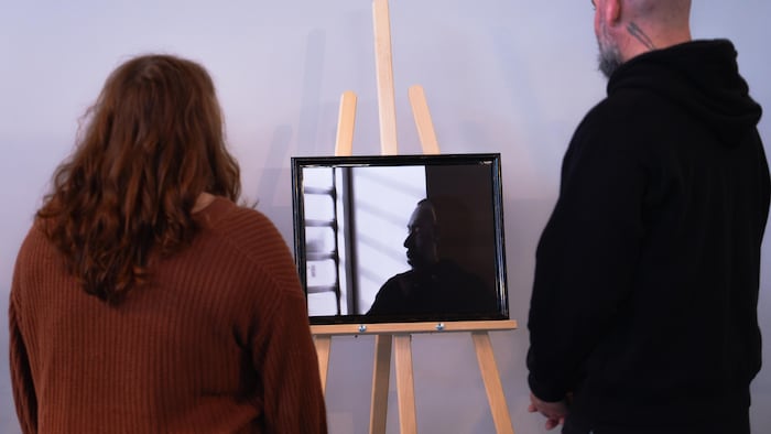Une femme et un homme qui observent une photographie installée sur un chevalet.