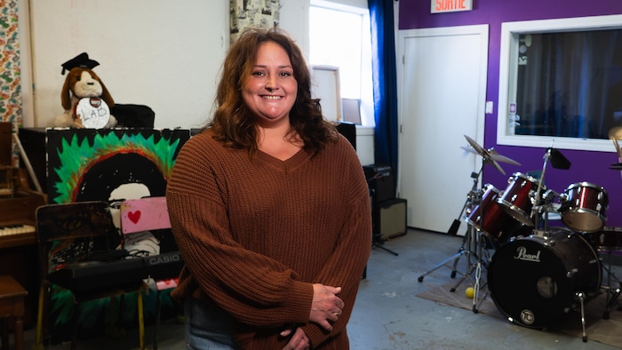 Une femme souriante qui pose devant des instruments de musique.