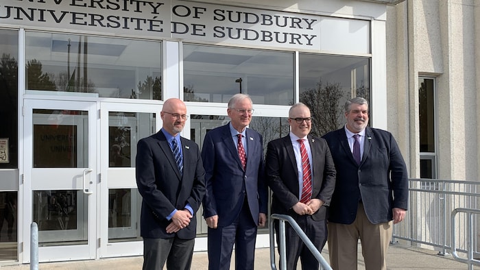 Quatre personnes, dont Jacques Frémont, recteur de l'Université d'Ottawa, Serge Miville, recteur de l'Université de Sudbury, et Peter Hominuk, directeur général de l'Assemblée de la francophonie de l'Ontario, posent debout pour une photographie sur les marches devant le bâtiment principal de l'Université de Sudbury.