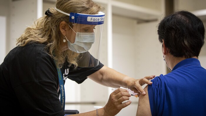 شاب يتلقى اللقاح المضاد لفيروس كورونا المستجد في أحد مراكز التلقيح في مدينة تورنتو عاصمة أونتاريو