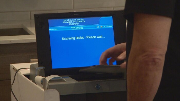 Une personne introduit son bulletin de vote dans une tabulatrice en Alberta dans cette photo prise le 27 mai 2023. 