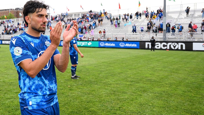 Un joueur de soccer applaudit sur un terrain.
